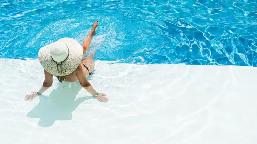 Women sitting on a sun shelf in a pool.