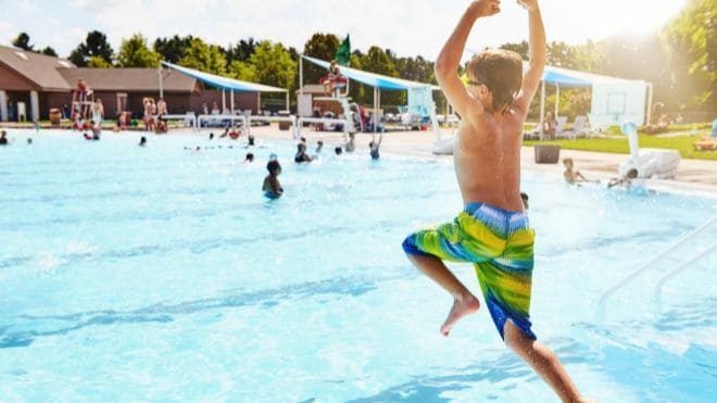 Boy jumping into public swimming pool